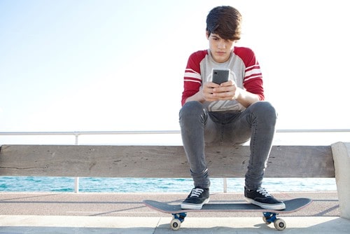 using-meditation-to-reduce-teen-addiction-to-screens boy reading text on phone