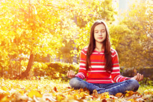 girl sitting in woods meditating