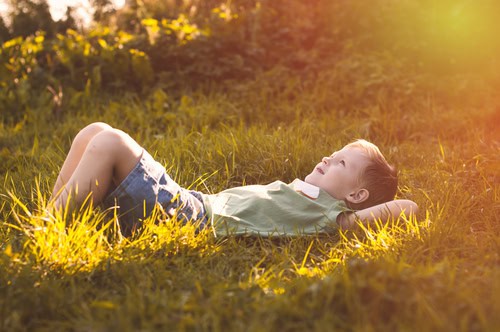 boy lying on grass looking at sky Help Young Minds Thrive – Exploring the Connected Kids Method